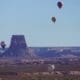 Three hot air balloons in various positions in the sky in Page, Arizona, for the annual Balloon Regatta.