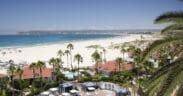 Hotel del Coronado's buildings and pool with the beach and bay of Coronado Island.