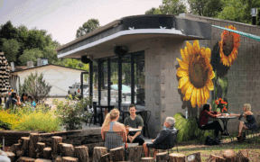 People sit outside of a Flagstaff business with giant painted sunflowers.