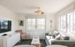 A TV, credenza, couch, chairs and coffee table inside a Bay Shores Peninsula Hotel suite.