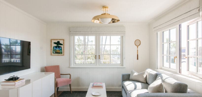 A TV, credenza, couch, chairs and coffee table inside a Bay Shores Peninsula Hotel suite.