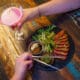 A woman holds a martini glass with a cocktail in it and a man eats sliced steak out of a bowl with chopsticks from CHoP Chandler.