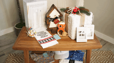 A SmartMouth dental gift set, The Collective, a baby rattle and onsie and other products from Chandler Fashion Center on a table.