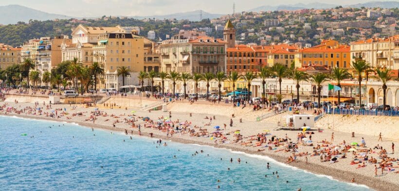 Coastal landscape with people resting on the beach along the Promenade des Anglais in Nice. French Riviera, France.