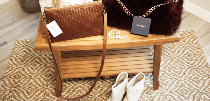 A leather woven purse, Arlo fur back with gold chain, otther bracelts and leather boots in a bright room.