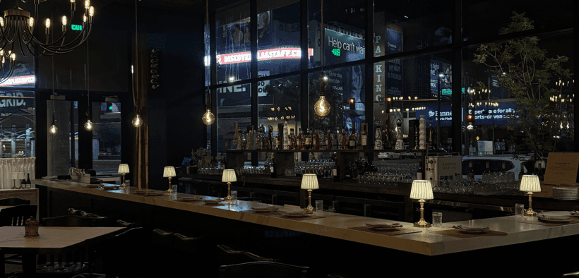 A hanging light hovers above a dimly lit single-diner square table at Humble Bistro.