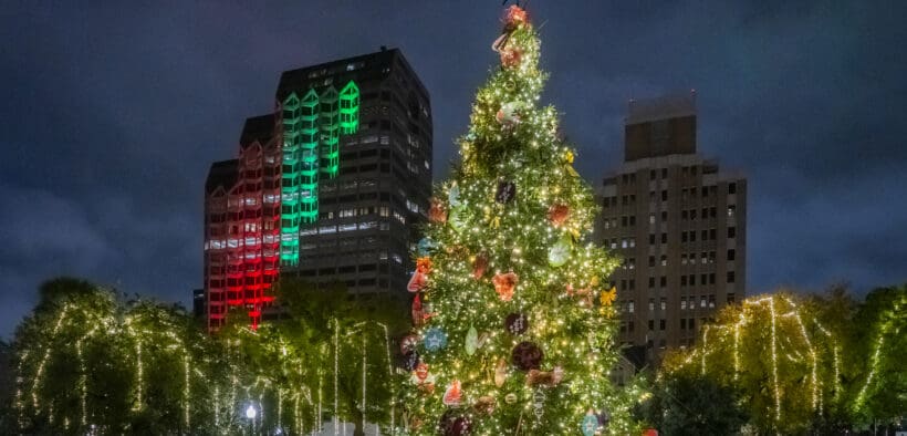 Downtown San Antonio at night with a lit Christmas trees and other lit up along the River Walk.