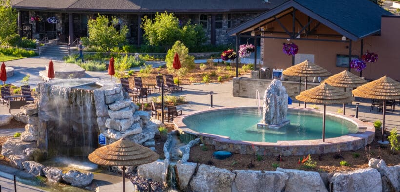 The Springs Resort lodge building with two geothermal pools in front with steam rising.