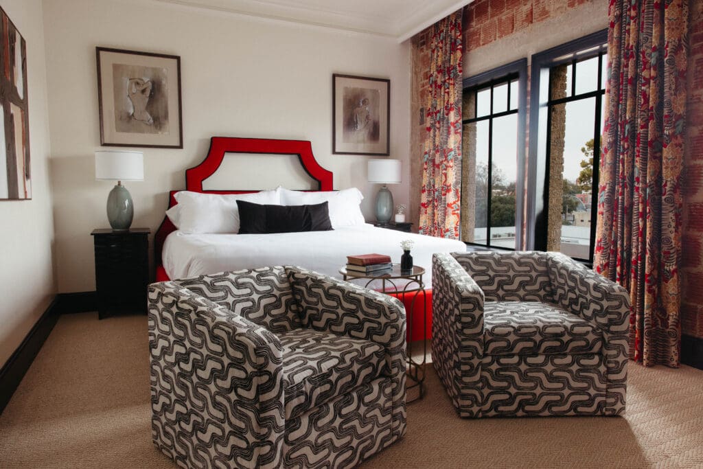 New Braunfels historic landmark, The Faust Hotel's renovated guestroom with a king bed and two stylish chairs.