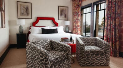 New Braunfels historic landmark, The Faust Hotel's renovated guestroom with a king bed and two stylish chairs.