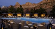 The Red Cliffs Lodge Zion pool and cabanas lit at night against the red cliffs of Zion.