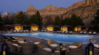 The Red Cliffs Lodge Zion pool and cabanas lit at night against the red cliffs of Zion.