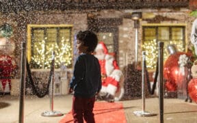 A child looks on as fake snow falls on a red carpet leading to Santa on his throne at Estancia La Jolla Hotel & Spa.