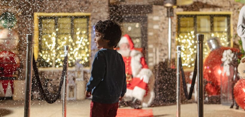 A child looks on as fake snow falls on a red carpet leading to Santa on his throne at Estancia La Jolla Hotel & Spa.