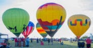 Five hot air balloons with varying designs, mostly with desert depictions at Wild Horse Pass for the Arizona Balloon Classic.
