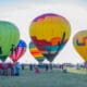 Five hot air balloons with varying designs, mostly with desert depictions at Wild Horse Pass for the Arizona Balloon Classic.