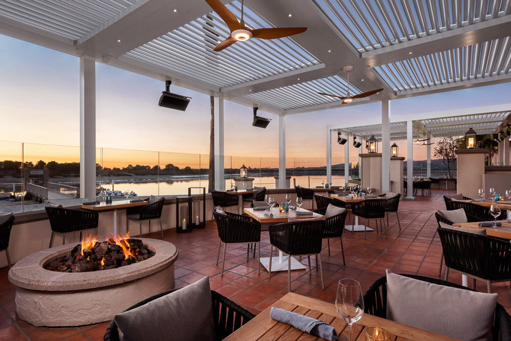 A fire pit, and set tables on a patio overlooking Mission Bay at San Diego Mission May Resort at the Covewood.