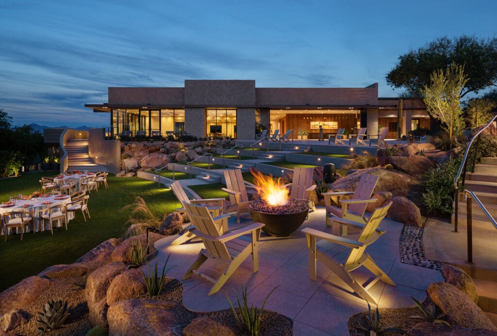 Fire bowl surrounded by seating on a landscaped event lawn at Sanctuary Camelback Mountain Resort & Spa at dusk