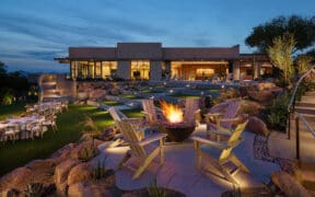 Fire bowl surrounded by seating on a landscaped event lawn at Sanctuary Camelback Mountain Resort & Spa at dusk