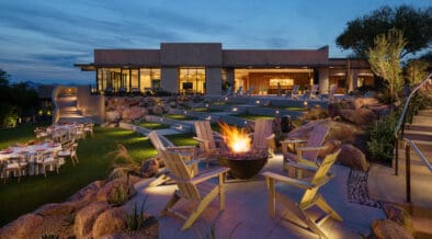 Fire bowl surrounded by seating on a landscaped event lawn at Sanctuary Camelback Mountain Resort & Spa at dusk