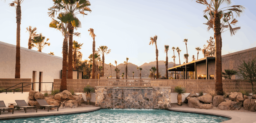 The pool at Kimpton Miralina Resort & Villas Paradise Valley surrounded by rocks and palm tree landscaping.