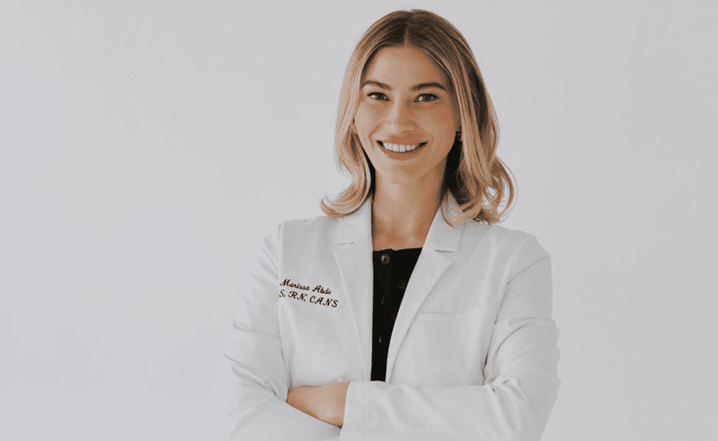 Marissa Abdo of Aesthetic IQ in Scottsdale wearing a white lab coat and smiling against a neutral background.