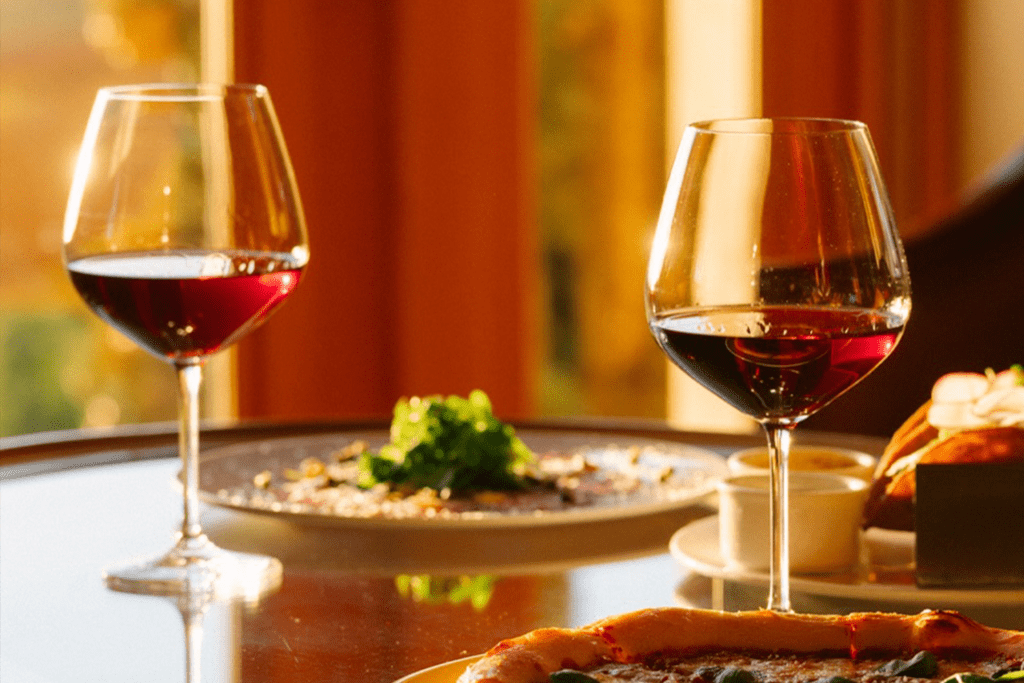 Romantic dining table at The Resort at Pelican Hill featuring red wine, plated entrées, and warm evening light, setting the scene for a Valentine’s Day dinner.