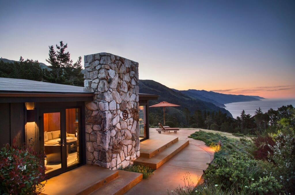 Private guest suite at Post Ranch Inn overlooking the Big Sur coastline at sunset, featuring stone architecture and panoramic ocean views.