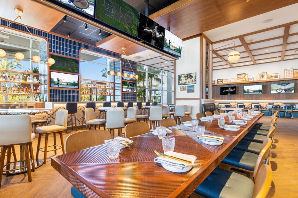 The Hilton San Diego Bayfront Hudson & Nash restaurant with set tables, hightops, bar area and TVs.