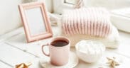 Valentine's Day trinkets, comfy knit blankets by the window, a frame and pink mug with marshmallow.