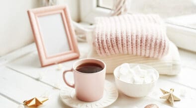 Valentine's Day trinkets, comfy knit blankets by the window, a frame and pink mug with marshmallow.