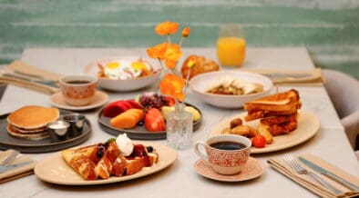 Breakfast spread at Poppy’s featuring pancakes, French toast, sandwiches, fruit, coffee and juice on a dining table.