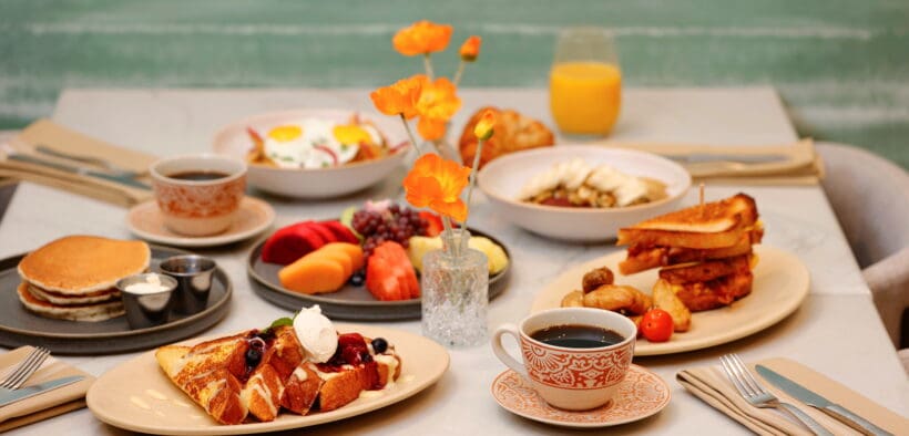Breakfast spread at Poppy’s featuring pancakes, French toast, sandwiches, fruit, coffee and juice on a dining table.