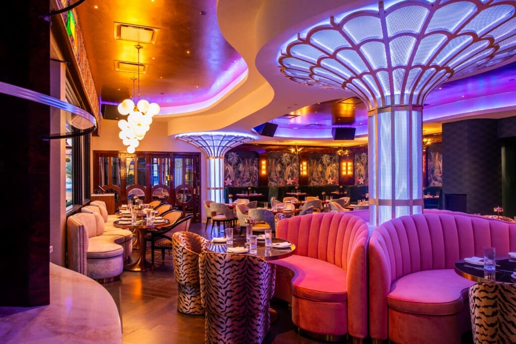 Interior dining room at JING Scottsdale featuring pink curved booths, dramatic ceiling lighting and glowing column fixtures.