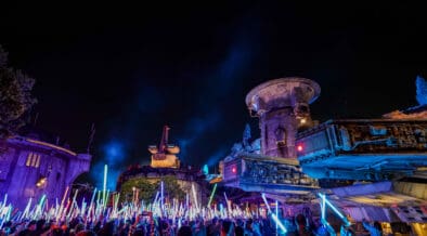 Disneyland After Dark Star Wars Nite with crowds waving illuminated lightsabers in Galaxy’s Edge after hours.