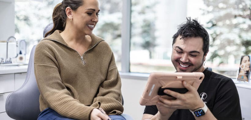 Provider reviewing treatment plan on an iPad with a patient inside Facial Aesthetics’ Westminster medical spa.