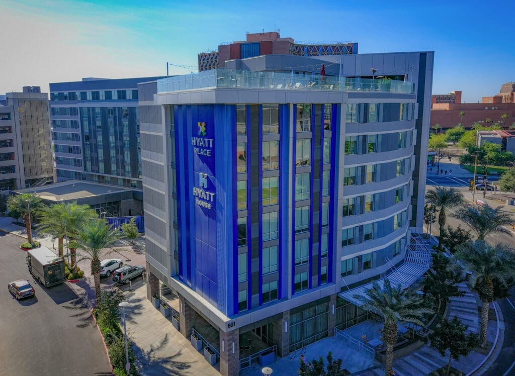 Exterior view of Hyatt Place and Hyatt House Tempe/Downtown near Novus Place with palm trees and modern architecture.