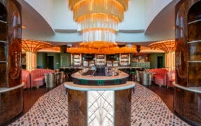 JING Scottsdale entry featuring a large gold chandelier, circular bar seating and art deco-inspired columns.