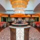 JING Scottsdale entry featuring a large gold chandelier, circular bar seating and art deco-inspired columns.