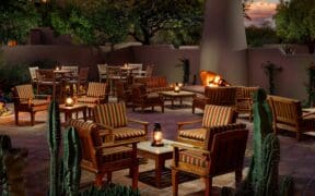 Exterior view of The Hermosa Inn with blooming bougainvillea, garden pathways, and Camelback Mountain in the background.