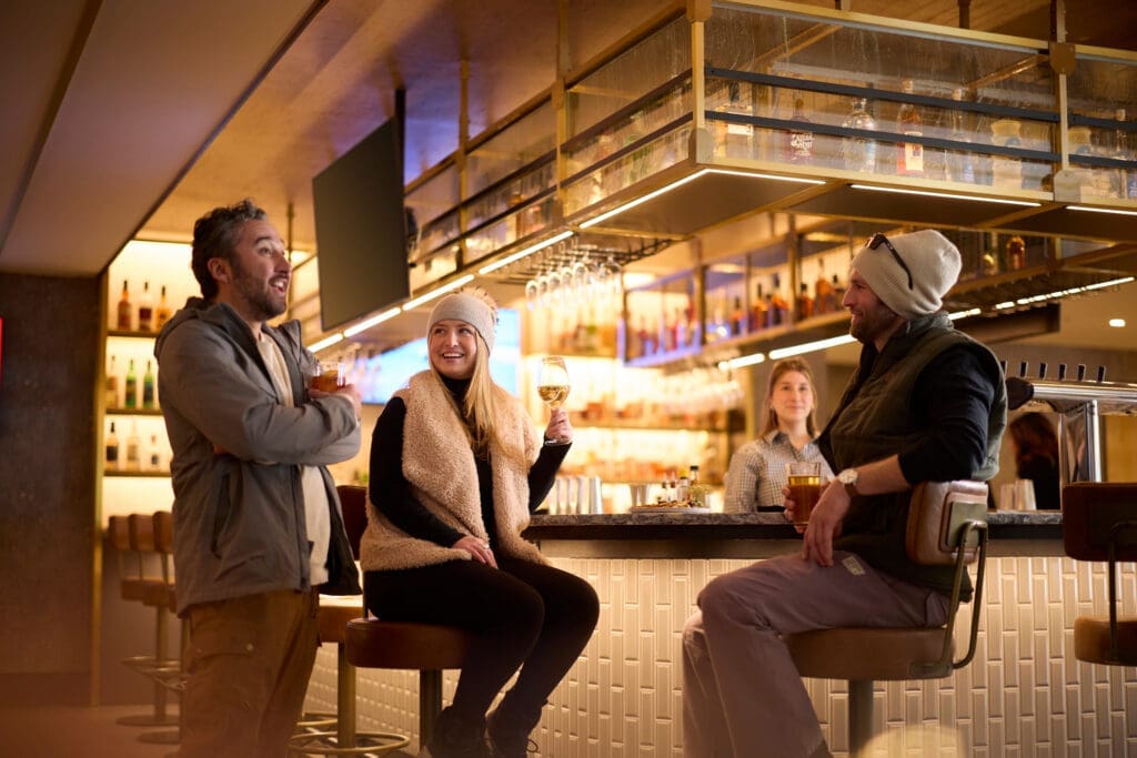Guests gather at The Carter bar at Hotel Alpenrock, enjoying cocktails and conversation during après ski in Breckenridge.