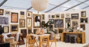 Gallery-style booth at the Marburger Farm Antique Show featuring framed artwork, vintage chairs, sculptural ceramics and wood furniture.