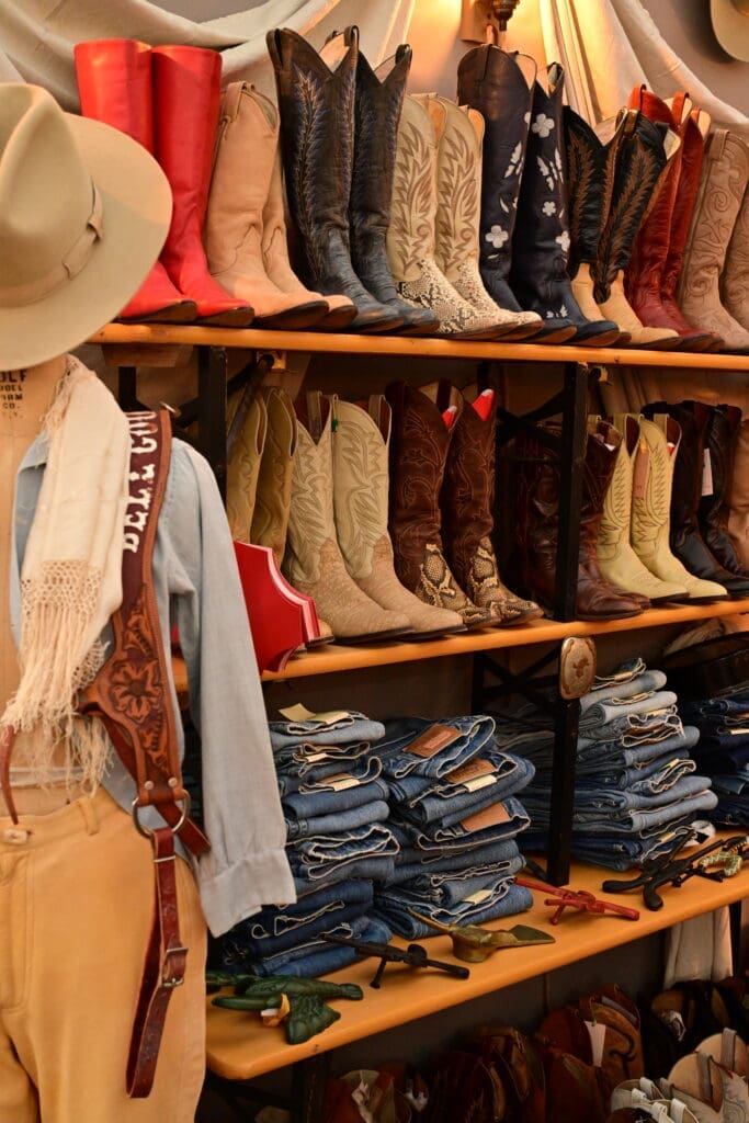 Vintage Western boots and folded denim displayed at a dealer booth at the Marburger Farm Antique Show Spring Show in Round Top.