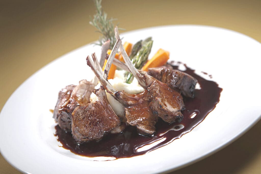 Romantic plated lamb chops al balsamico at Marcellino Ristorante, served over creamy mashed potatoes with asparagus, carrots and a rich balsamic reduction.
