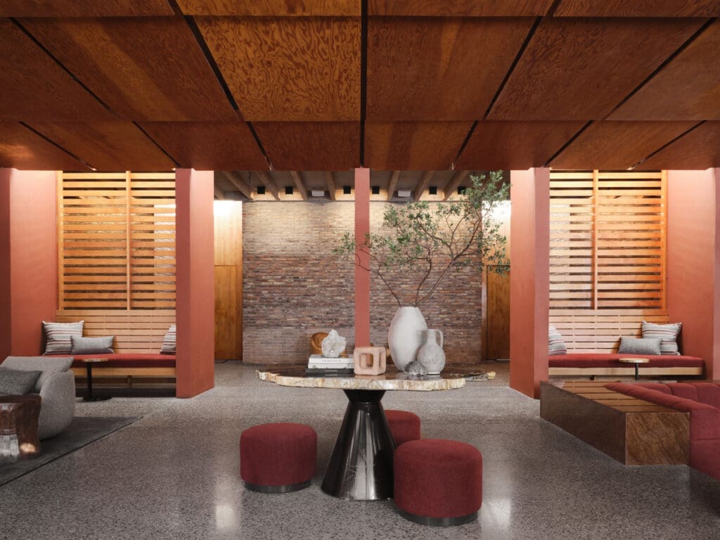 Interior of Mii amo spa in Sedona, Arizona, featuring terracotta columns, wood ceiling panels, built-in bench seating and a central stone table with decorative vases and plants.