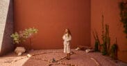 A guest in a robe stands inside a circular stone labyrinth courtyard at Mii amo in Sedona, Arizona, surrounded by terracotta walls, desert landscaping and soft natural light.