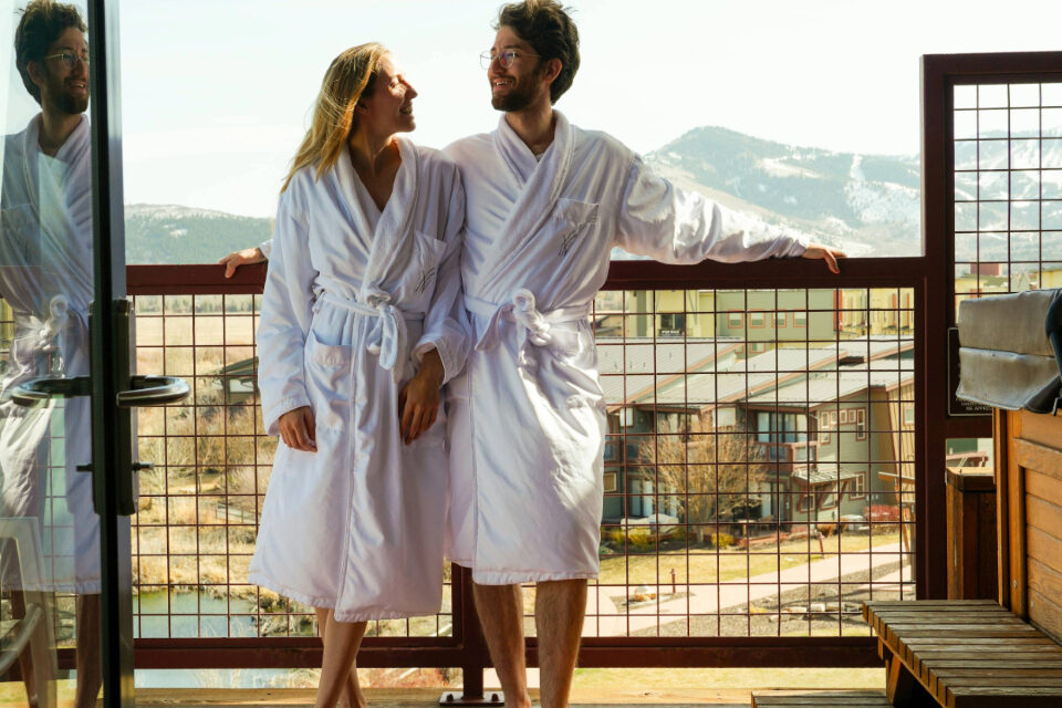 Couple in robes enjoying mountain views from a private balcony at Newpark Resort in Park City, Utah.