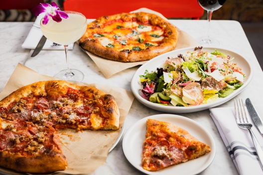 Wood-fired pizzas, a fresh green salad and a cocktail served on a marble table at North Italia in Novus Place Tempe.