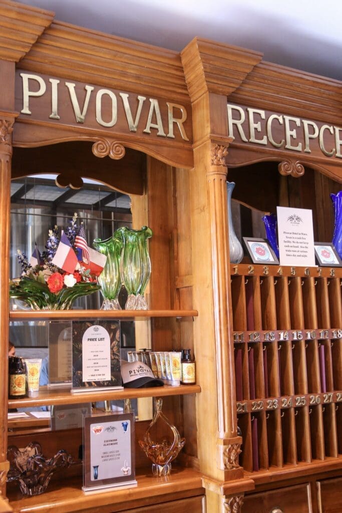 Wood-paneled reception desk at Pivovar Hotel in Waco, Texas with vintage-style mail slots and glass décor.