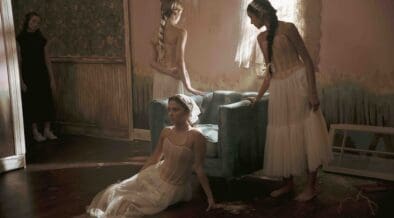 Dancers in soft, neutral costumes pose inside a vintage-style room with textured walls and dramatic lighting in a scene from the Arizona-made cine-dance film Rooms, screening February 24 in Tucson.